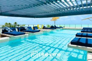 a swimming pool with blue lounge chairs and the ocean at Setai Aquamaris - LikeHome Hospedagens in Tambaú