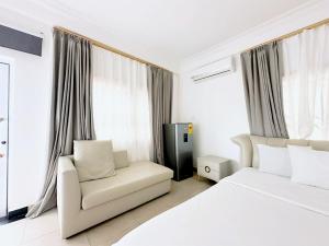 a bedroom with a white bed and a chair at Golden Crystal Hotel in East Legon in Accra +25 photos