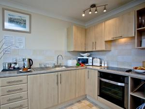 a kitchen with wooden cabinets and a sink at 3 Linden Court in Brixham