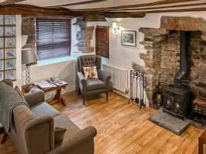 ein Wohnzimmer mit einem Steinkamin und einem Stuhl in der Unterkunft Greystones in Kirkby Stephen