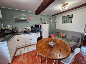 a kitchen and living room with a wooden table at Studio Bienvenue du côté de chez nous avec jardin privatif in Wignehies