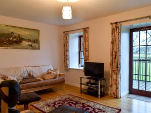 ein Wohnzimmer mit Sofa und Fernseher in der Unterkunft Diggers Cottage in Oxton