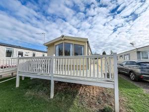 a house with a white fence and a car at Caravan With Decking Within Walking Distance To Hunstanton Beach Ref 23054S in Hunstanton