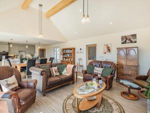 a living room with leather furniture and a kitchen at Lizzie's Cottage in Skendleby