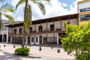 a building with a balcony and a palm tree at Hotel Colonial Andino - Parque principal de Pitalito in Pitalito