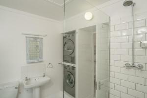ein Badezimmer mit Dusche und Waschmaschine in der Unterkunft Oceanside Cottage in Rocklands
