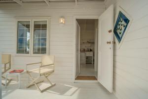 eine weiße Veranda mit einem Stuhl und einem Tisch in der Unterkunft Oceanside Cottage in Rocklands