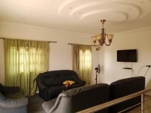 a living room with two leather couches and a television at Villa BLESSING in Komé