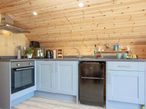 a kitchen with white cabinets and a wooden ceiling at Glamping Pod 1 in Ipplepen
