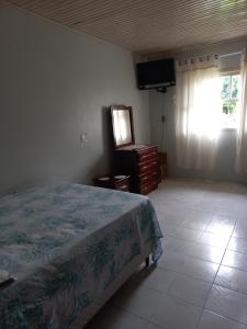 a bedroom with a bed and a dresser and a television at Casa Azul da Marina in Três Coroas