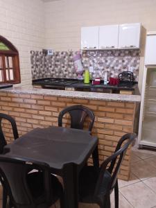 une cuisine avec une table, des chaises et une cuisinière dans l'établissement Casa com cozinha americana, à Araruama