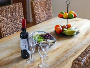 Una botella de vino sentada en una mesa de madera con copas en Beudy-Oh2, en Dihewid