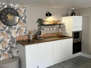 a kitchen with white cabinets and a clock on the wall at Cléanounette du Morvan in Saulieu