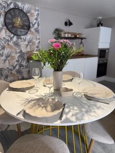 a table with plates and glasses and a vase with flowers at Cléanounette du Morvan in Saulieu