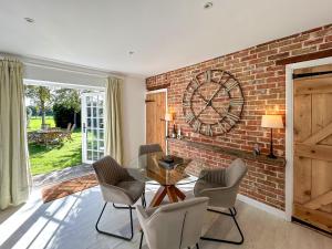 a dining room with a brick wall and a clock at The Cottage - Uk50673 in Tangmere