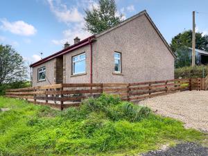 a house with a wooden fence in front of it at Acreknowe Cottage in Hawick