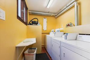 a laundry room with yellow walls and white cabinets at Edgemont C1 in Killington Village +11 photos