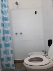 des toilettes blanches dans une salle de bain avec un rideau de douche bleu dans l'établissement La Vecindad del Sol Depto H, à Miramar