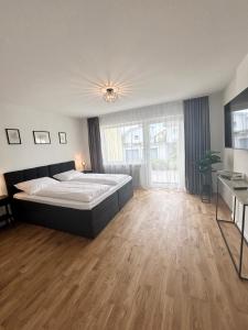1 dormitorio grande con 1 cama y suelo de madera en Basilisk Homes - in Grenzach-Wyhlen bei Basel - 4 x Moderne Fewos je 1bis2, 1bis4 oder 1bis6 Pers mit Küche und Balkon oder Terrasse - Parkplätze vorhanden, en Grenzach-Wyhlen