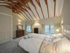 une chambre avec un grand lit blanc avec un plafond en bois dans l'établissement Holliers Cottage, à Ledwell