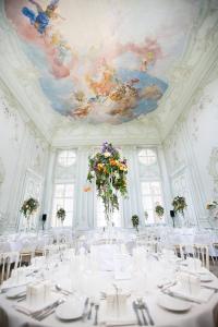 a dining room with white tables and a ceiling with paintings at Knappenstöckl in Halbturn
