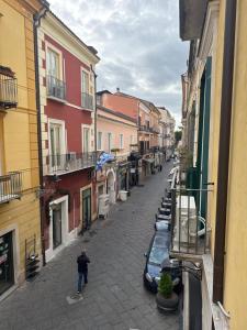 un hombre caminando por una calle con coches aparcados en InCentro, en Caserta