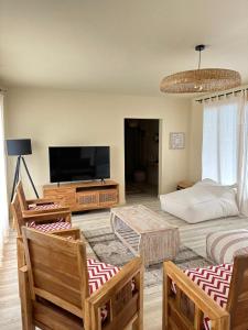 a living room with a flat screen tv and chairs at Les Hauteurs de Brûlée in Rodrigues Island