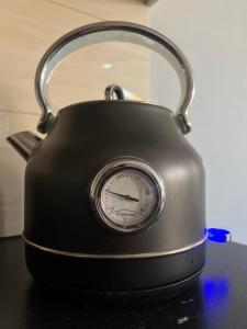 a black tea kettle with a clock on a table at EUROPA22 Apartament RELAKS z JACUZZI w samym sercu miasta Prestiżowe osiedle z widokiem na park i staw z fontannami Szybkie i Łatwe Zameldowanie in Tomaszów Mazowiecki