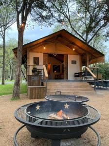 a fire pit in front of a building with a grill at Premium Lakefront Cabin 1 The Armadillo in Bastrop