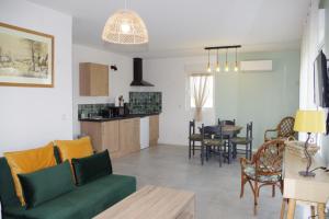 a living room with a green couch and a kitchen at Les Blés d'Or - Parking privé, Terrasse, Clim, Netflix, Au Calme in Hem-Lenglet