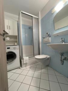 a bathroom with a toilet and a sink and a washing machine at See und Kliniknahes Apartment, Balkon, Wifi, Blick ins Grüne in Prien am Chiemsee