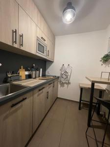 a kitchen with wooden cabinets and a sink and a table at See und Kliniknahes Apartment, Balkon, Wifi, Blick ins Grüne in Prien am Chiemsee