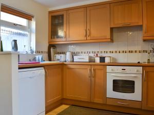 a kitchen with wooden cabinets and white appliances at Bruich Cottage in Newtonmore +12 photos