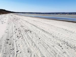 a beach with tire tracks in the sand and water at Sea side home in Jūrmala