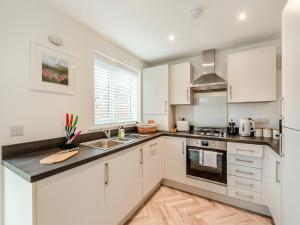 eine Küche mit weißen Schränken und einer Spüle in der Unterkunft Pelican Rest - Uk41429 in Amble