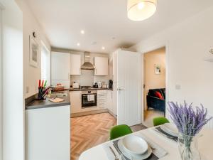 eine Küche mit weißen Schränken und einem Tisch mit grünen Stühlen in der Unterkunft Pelican Rest - Uk41429 in Amble