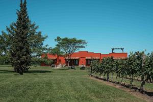 a red building with a row of trees in a field at Los Muelles Boutique Hotel in Carmelo