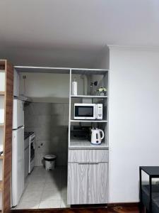 a small kitchen with a microwave and a refrigerator at Departamento Frente Campus UNC in Cordoba +3 photos