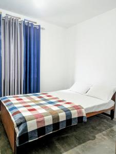 エッラにあるFelix Holiday Bungalowの青いカーテンが備わるドミトリールームのベッド1台分です。