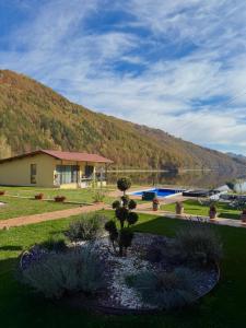 a house with a pond in front of a mountain at Complex Brădișor in Malaia