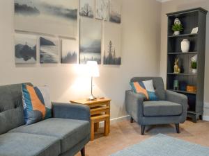 ein Wohnzimmer mit zwei Stühlen und einer Couch und einer Lampe in der Unterkunft Blackmill Cottages No 2 in Taynuilt