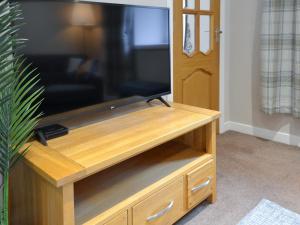 einen Flachbild-TV auf einem hölzernen Entertainment-Center in der Unterkunft Blackmill Cottages No 2 in Taynuilt