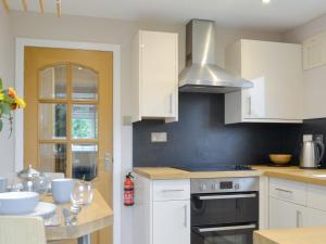 eine Küche mit weißen Schränken und einem Herd mit Backofen in der Unterkunft Blackmill Cottages No 2 in Taynuilt + 7 Fotos