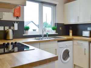 a kitchen with a sink and a washing machine at Blackmill Cottages No 2 in Taynuilt +6 photos