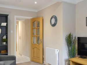 a living room with a clock on the wall at Blackmill Cottages No 2 in Taynuilt