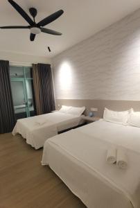 two beds in a hotel room with a ceiling fan at Seaview Cozy BS Homestay in Kota Kinabalu