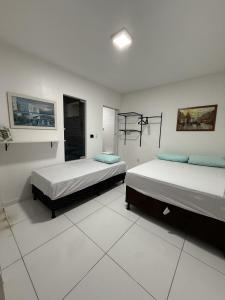 zwei Betten in einem Zimmer mit weißen Wänden in der Unterkunft Brisas Beach casa 05 in Praia do Frances