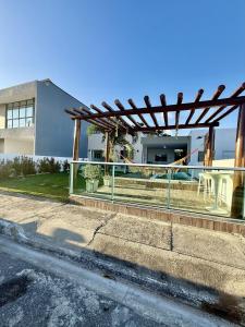 ein Gebäude mit einer hölzernen Pergola neben einer Straße in der Unterkunft Brisas Beach casa 05 in Praia do Frances