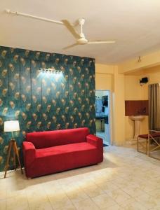 un sofá rojo en una sala de estar con una pared en Sunrise Homestay & Lodge, en Guwahati