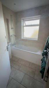 ein weißes Badezimmer mit Badewanne und Fenster in der Unterkunft Bling Paradise in Potters Bar